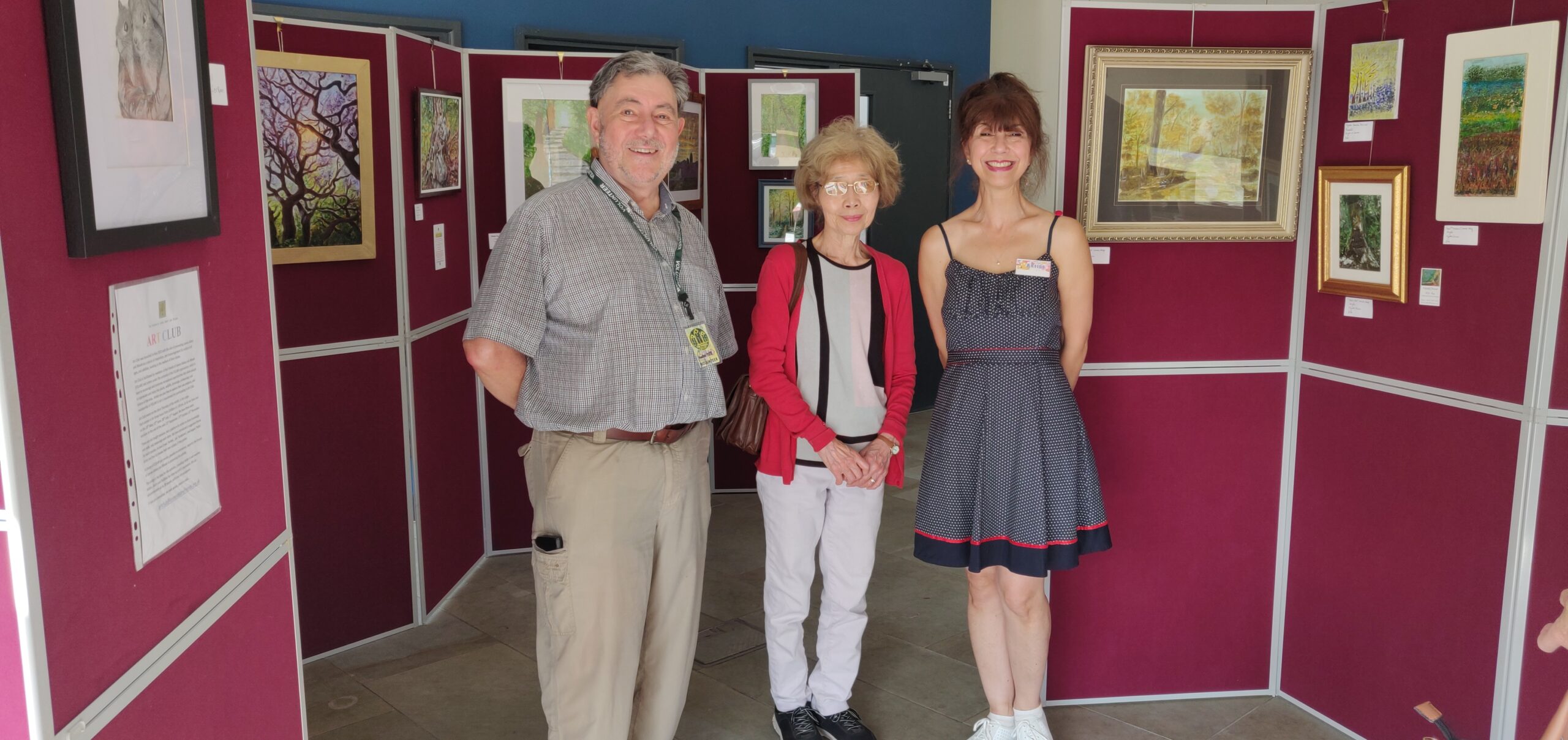 3 adults standing in front of an art exhibition